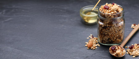 Homemade granola with nuts and dried fruits on gray table. Banner design with space for text