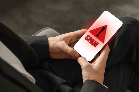 Man using smartphone indoors, closeup. Spam message notification on device screen, illustrationの写真素材