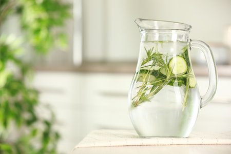 Refreshing cucumber water with rosemary in jug on white table, closeup. Space for textの写真素材