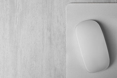 One wireless mouse with mousepad on gray wooden table, top view. Space for text