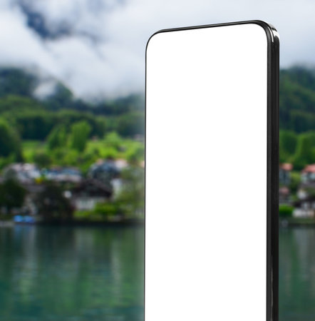 Mobile phone with empty screen against beautiful landscape. Space for designの写真素材