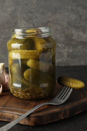 Pickled cucumbers in jar and garlic on gray tableの写真素材