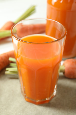 Healthy juice and fresh carrots on white wooden table, closeupの写真素材