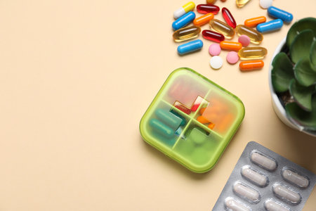 Different pills, organizer and succulent on beige background, flat lay. Space for textの写真素材