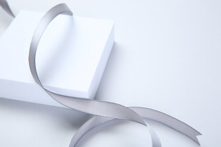 Beautiful gray ribbon and podium on white background, closeup. Space for textの写真素材