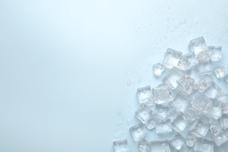 Crystal clear ice cubes on light blue background, flat lay. Space for text
