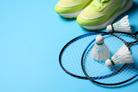 Feather badminton shuttlecocks, rackets and sneakers on light blue background, space for textの写真素材