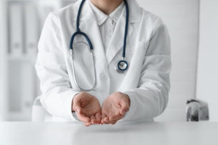 Doctor with stethoscope holding something at table in clinic, closeupの写真素材