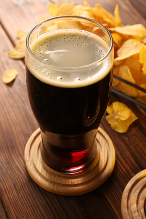 Glass of beer and potato chips on wooden table, closeupの写真素材