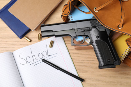 Gun, bullets and school stationery on wooden table, flat layの写真素材