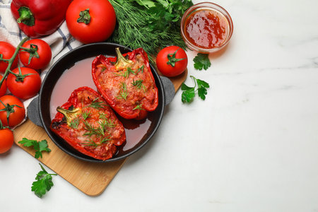 Tasty stuffed peppers in dish and ingredients on white table, flat lay. Space for textの写真素材