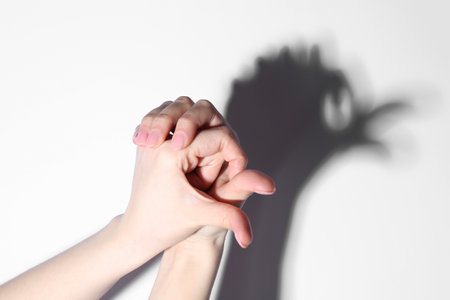 Shadow puppet. Woman making hand gesture like bird on light background, closeup