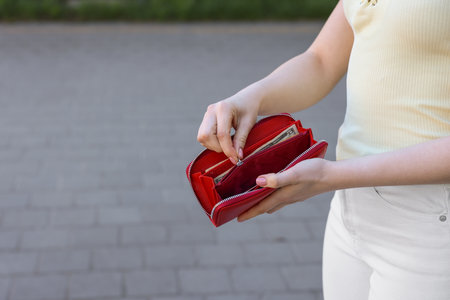Woman holding purse with banknotes outdoors, closeup. Space for textの写真素材