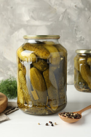 Pickled cucumbers in jar and spices on white tableの写真素材
