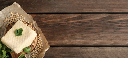 Delicious tofu, soybeans and parsley on wooden table, top view with space for text. Banner design