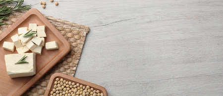 Delicious tofu, soybeans and rosemary on light textured table, flat lay with space for text. Banner...