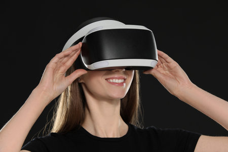Smiling woman using virtual reality headset on black background