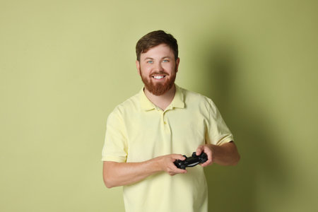 Happy man with game controller on pale green background
