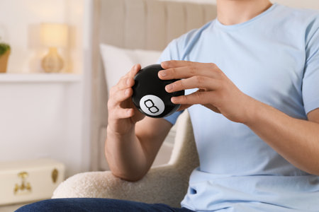 Man holding magic eight ball indoors, closeup