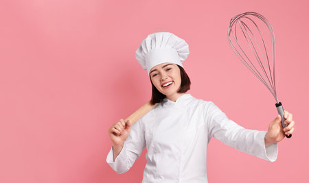 Happy pastry chef with big whisk and rolling pin on pink background. Banner designの写真素材