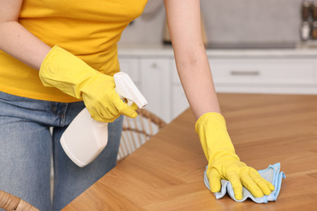 Professional janitor wearing uniform cleaning table in kitchen, closeupの写真素材