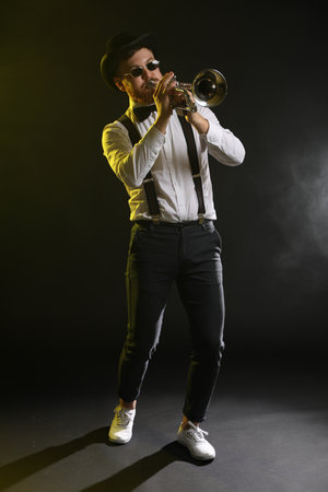 Professional musician playing trumpet on black background in color lightsの写真素材