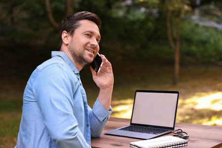 Smiling freelancer talking on smartphone outdoors. Remote jobの写真素材