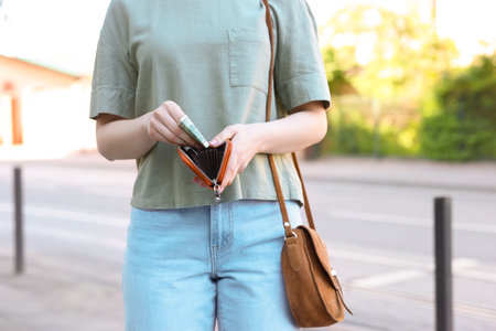 Woman holding purse with banknotes outdoors, closeupの写真素材