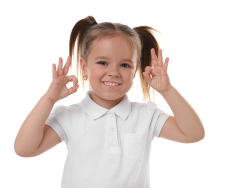 Portrait of happy little girl showing OK gesture on white backgroundの写真素材