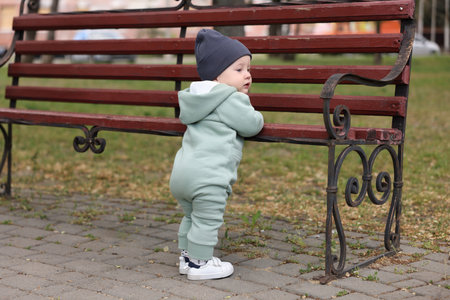 Little baby learning to walk near bench in parkの写真素材