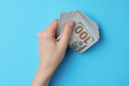 Money exchange. Woman holding dollar banknotes on light blue background, top viewの写真素材