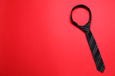 Striped necktie on red background, top view. Space for textの写真素材