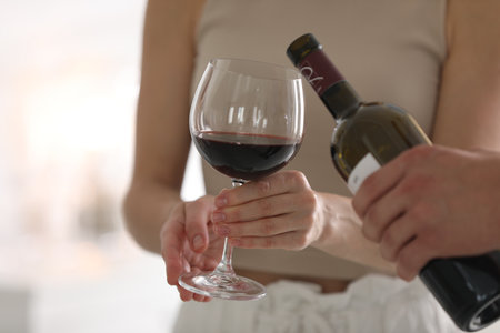Man pouring red wine into woman`s glass indoors, closeupの写真素材