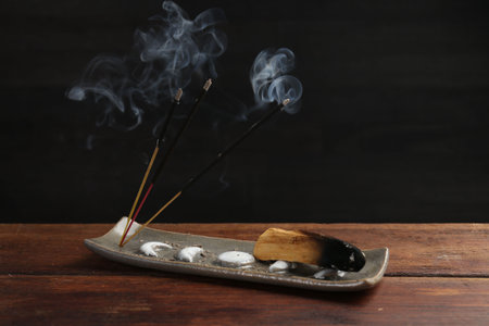 Aromatic incense sticks smoldering on wooden table. Space for text