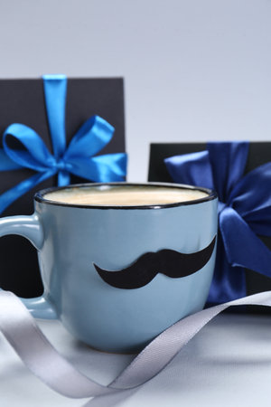 Happy Father's Day. Cup of coffee with funny moustache and gift boxes on light backgroundの写真素材