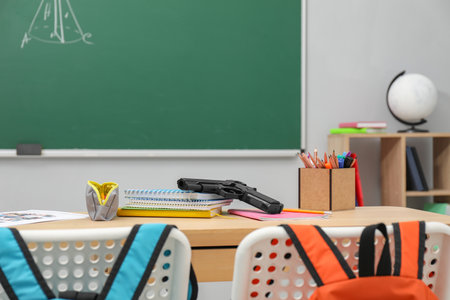 School stationery and gun on desk in classroomの写真素材