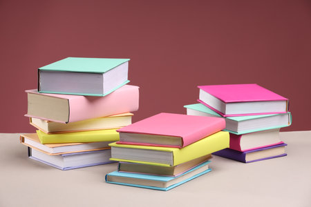 Many colorful books on beige table against pink backgroundの写真素材