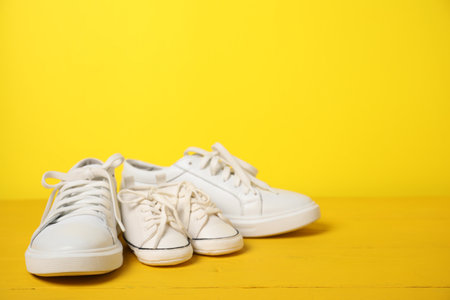 Big and small sneakers on yellow background. Space for textの写真素材