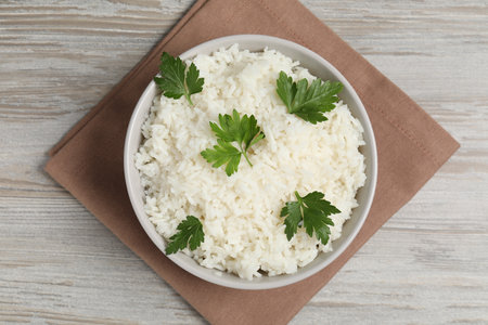 Tasty cooked rice with parsley in bowl on wooden table, top viewの写真素材