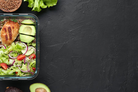 Healthy meal. Fresh salad, avocado, cutlet and buckwheat in glass container near other products on black table, flat lay. Space for textの写真素材