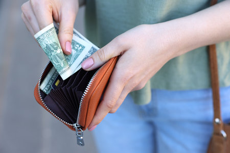 Woman holding purse with banknotes outdoors, closeupの写真素材