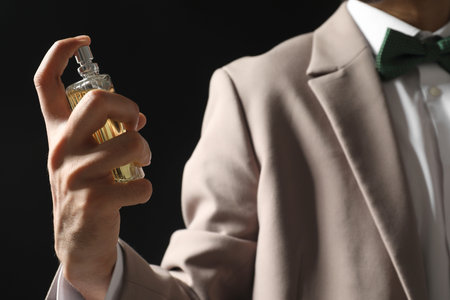 Man spraying luxury perfume on dark background, closeupの写真素材