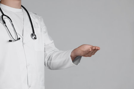 Doctor holding something on grey background, closeupの写真素材