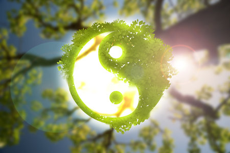 Yin and yang symbol with green leaves against blurred tree branchの写真素材