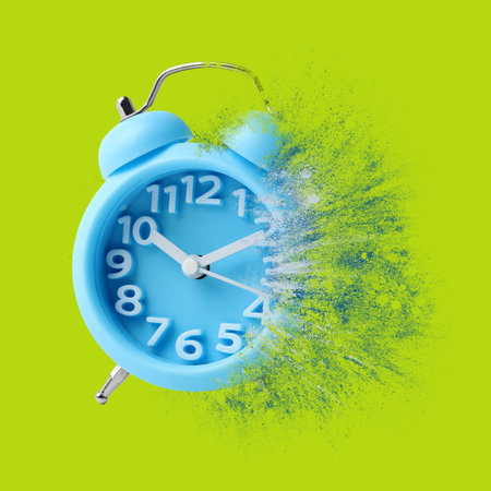 Light blue alarm clock dissolving on green background. Flow of timeの写真素材