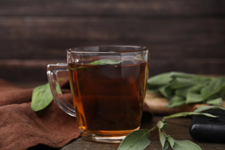 Aromatic herbal tea in cup with sage on wooden table, closeupの写真素材