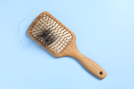 Wooden brush with lost hair on light blue background, top viewの写真素材