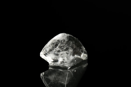 Piece of clear ice on black mirror surfaceの写真素材