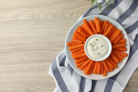 Baby carrots and sauce on wooden table, top view. Space for textの写真素材