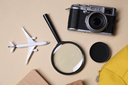 Travel blogger. Flat lay composition with vintage camera and magnifying glass on beige backgroundの写真素材